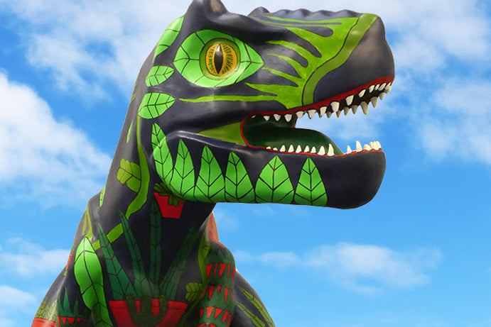 Close up of a painted t-rex head sculpture with a blue sky full of clouds in the backgroundUp close of a painted dinosaur mouth for go go dinosaurscatcusaurus dinosaur at QD anglia square in norwich